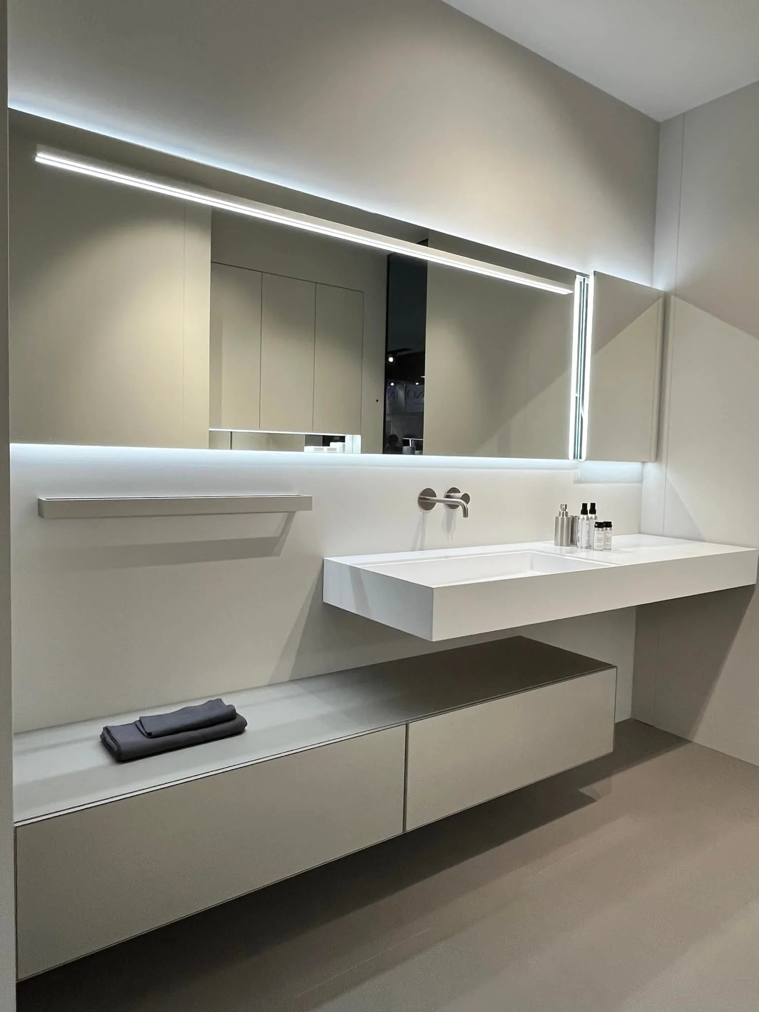 Salle de bain moderne avec vasque suspendue, mobilier intégré et éclairage LED